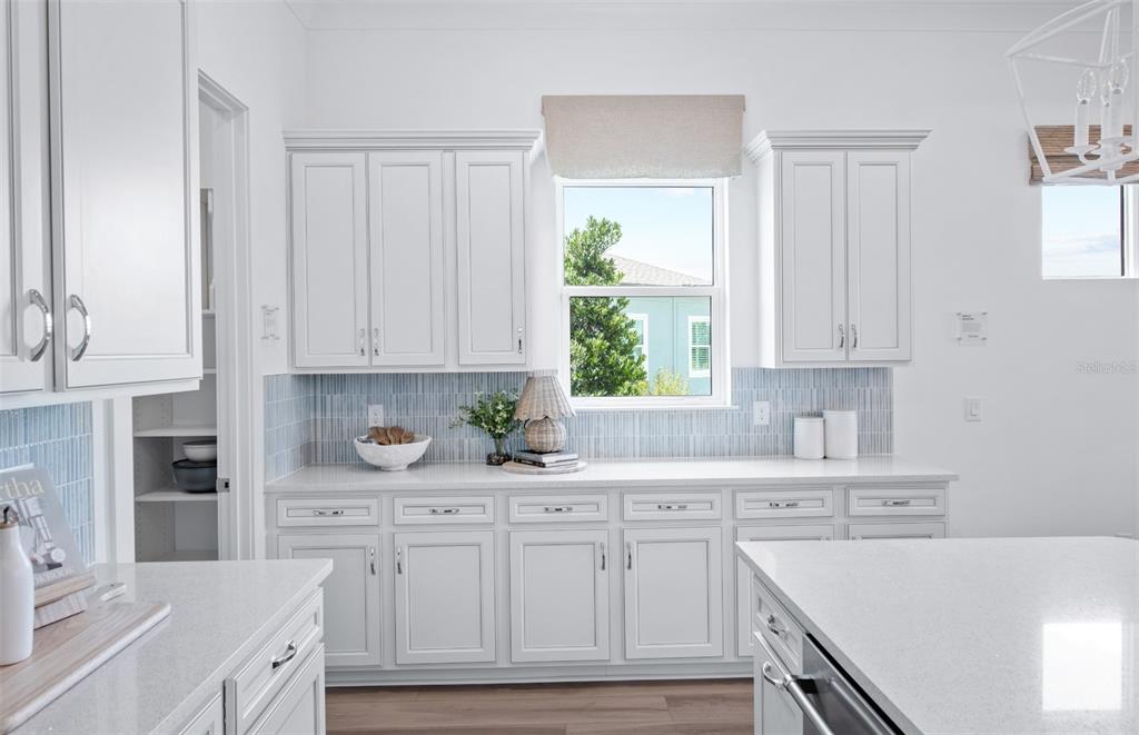 A bright kitchen features white cabinetry, a light blue tiled backsplash, and white quartz countertops — 11316 CLAY AVENUE, PARRISH, FL
