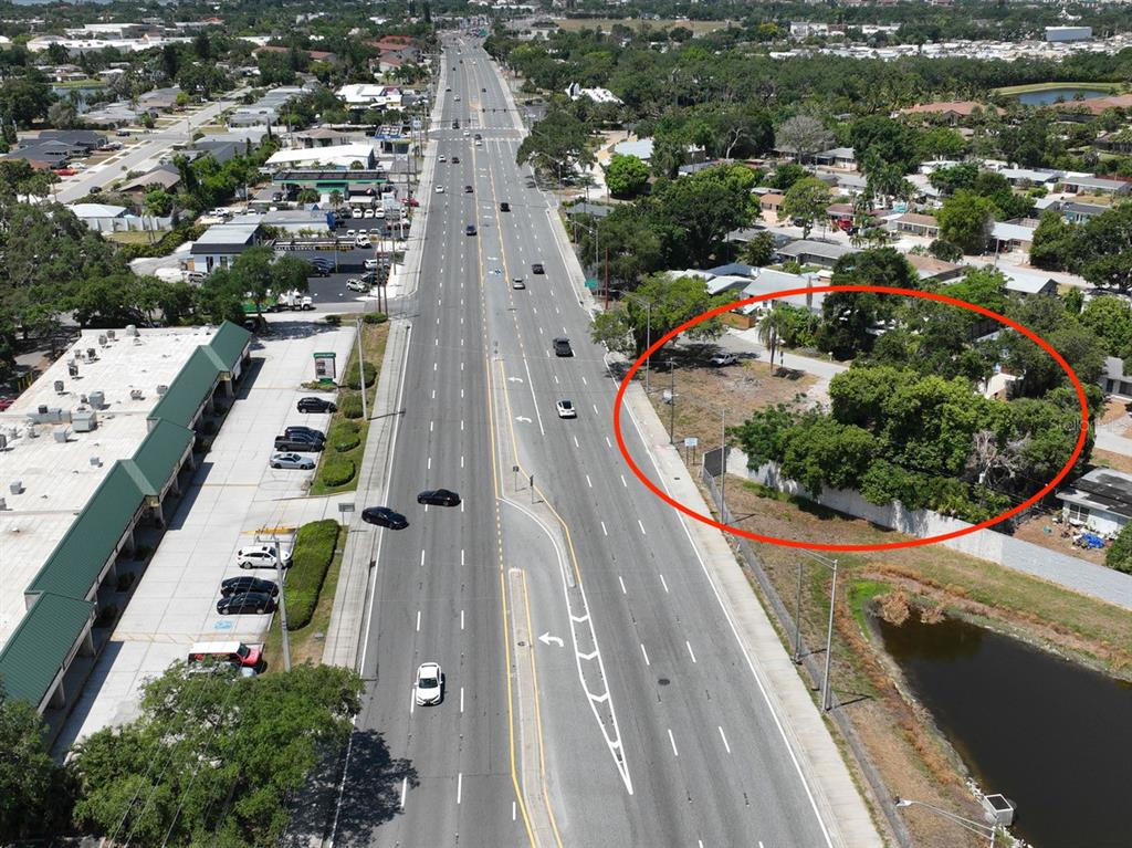 An aerial view shows a vacant, tree-covered lot adjacent to a multi-lane road — ALBERT PLACE, SARASOTA, FL