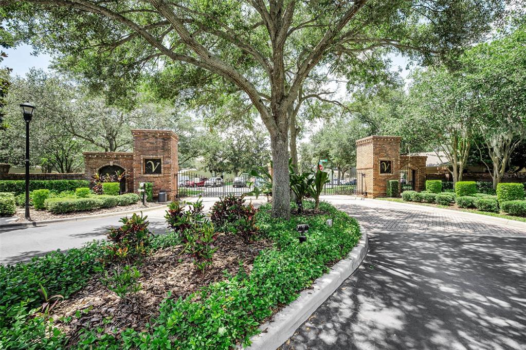 A two-story townhouse exterior features a gray facade, multiple garage doors, and a large tree — 10155 HAVERHILL RIDGE DRIVE, RIVERVIEW, FL
