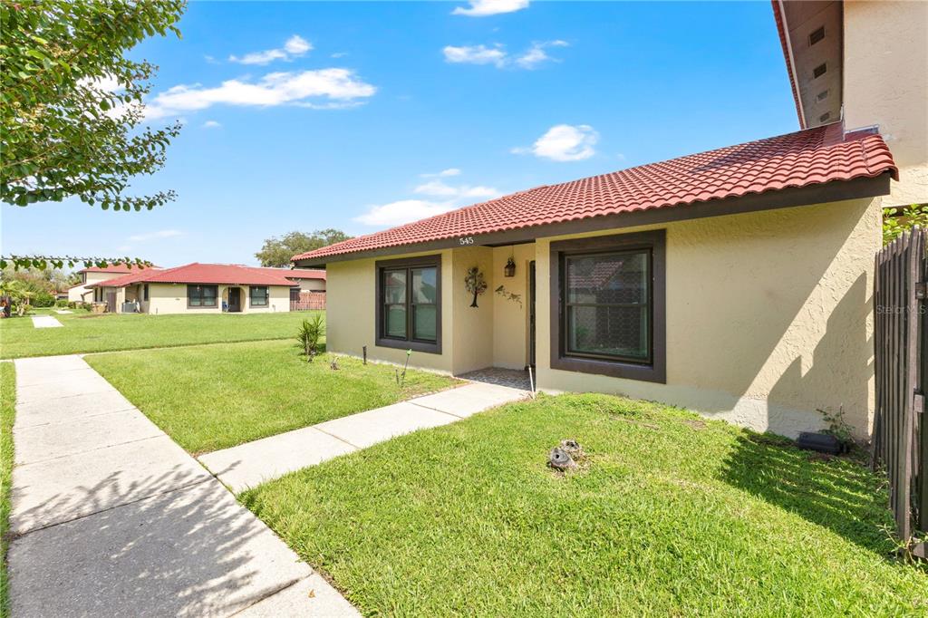 A single-story house with a tan stucco exterior, brown trim, and a red tiled roof — 545 HUNTER CIRCLE, KISSIMMEE, FL