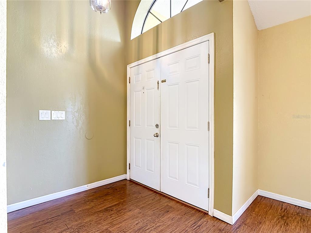 An entryway features white double doors, light-colored walls, and dark wood-look flooring — 2108 JONATHAN LANE, WINTER HAVEN, FL