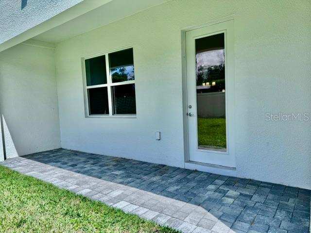 A paved patio sits outside a white exterior wall with a window and glass door — 1519 HERITAGE PLACE, OVIEDO, FL