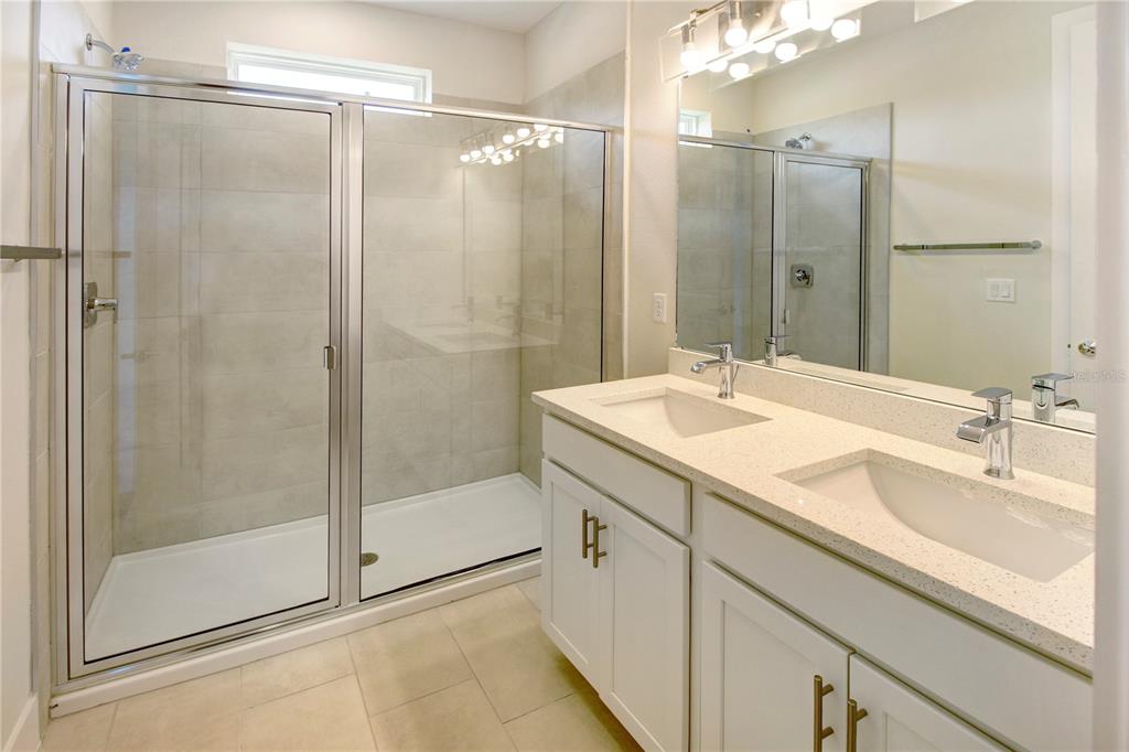 A bathroom features a double vanity with white cabinets and a glass-enclosed walk-in shower — 1519 HERITAGE PLACE, OVIEDO, FL