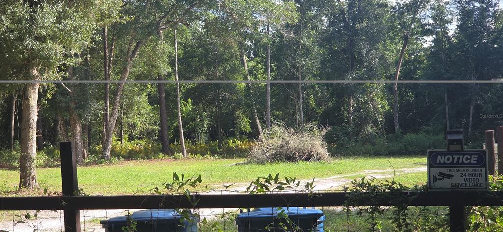 A grassy lot with a pile of brush is viewed through a wooden fence — 407 RAULERSON ROAD, SEVILLE, FL