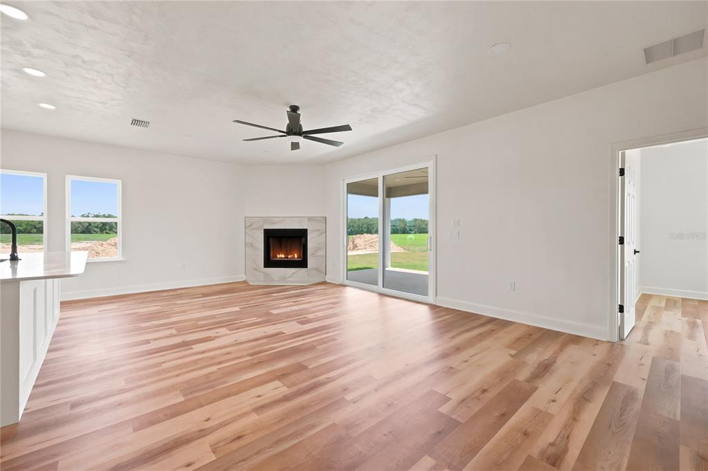 This is a digital rendering of an empty room with wood-look flooring and sliding glass doors — 21115 SW 1ST PLACE, NEWBERRY, FL