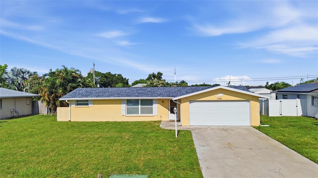 A single-story yellow house with a white garage door and a concrete driveway — 1786 COCONUT DRIVE, VENICE, FL
