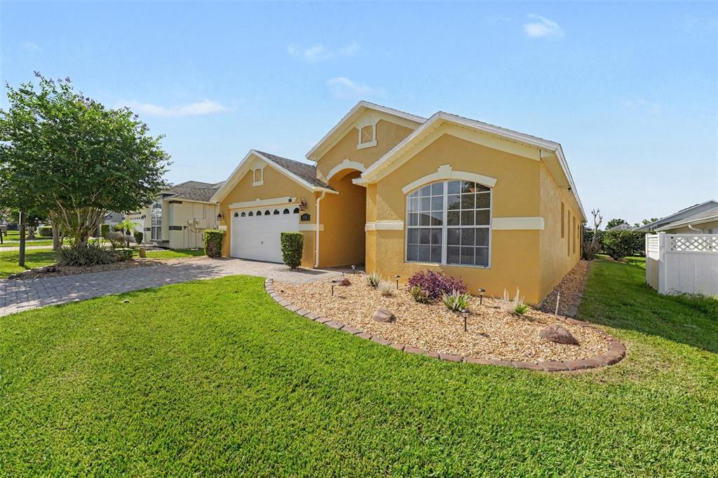 A yellow single-story house with a two-car garage and a landscaped front yard — 131 OLD BRIDGE CIRCLE, DAVENPORT, FL