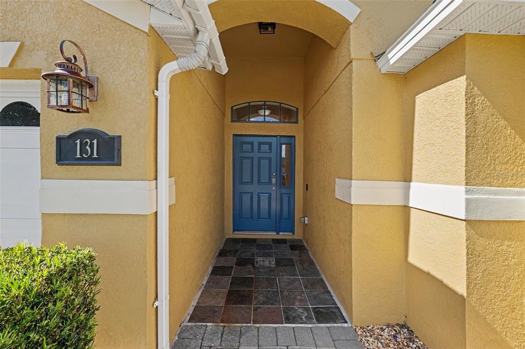 A blue front door is set within a recessed entryway with tiled flooring — 131 OLD BRIDGE CIRCLE, DAVENPORT, FL