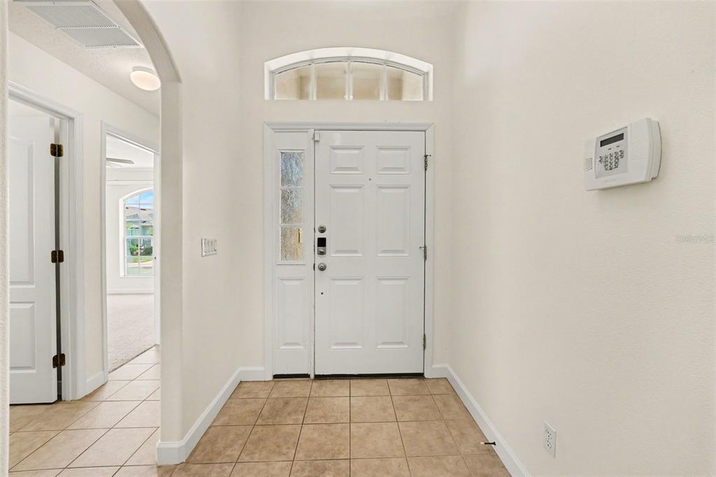 A tiled entryway features a white front door with a sidelight and an arched transom window — 131 OLD BRIDGE CIRCLE, DAVENPORT, FL