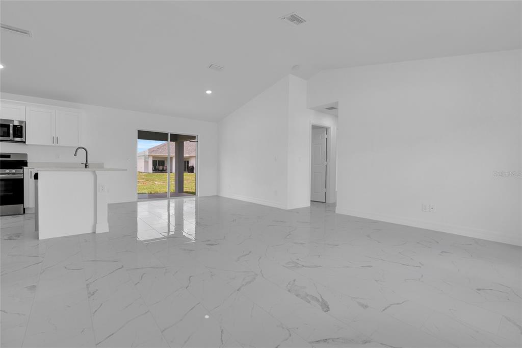 A modern kitchen features white cabinets, stainless steel appliances, and a quartz-topped island — 1808 NE 44TH STREET, CAPE CORAL, FL