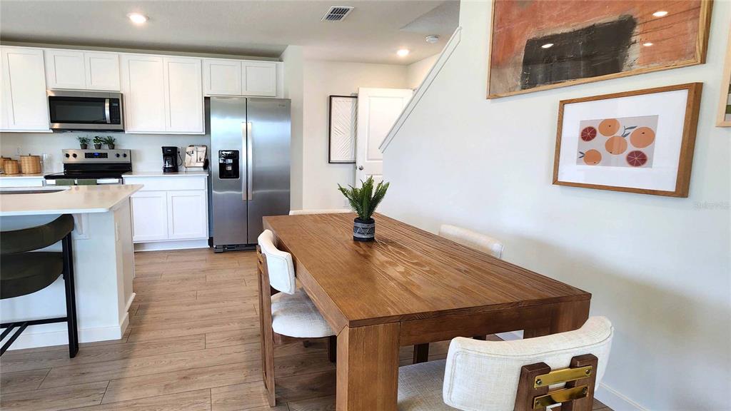 A dining area with a wooden table sits adjacent to a kitchen with white cabinets — 479 REMICK STREET, OSTEEN, FL