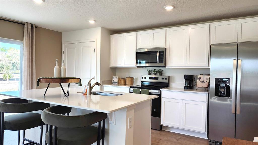 A modern kitchen features white cabinets, stainless steel appliances, and a large central island — 479 REMICK STREET, OSTEEN, FL