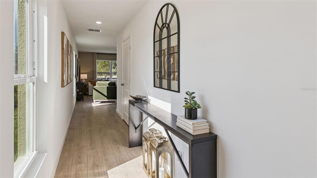 A hallway features wood-look flooring, a console table with decor, and an arched wall mirror — 479 REMICK STREET, OSTEEN, FL