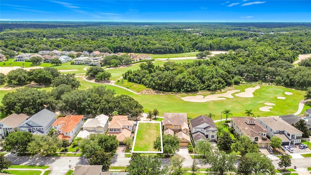 An aerial view shows a vacant residential lot situated between two houses on a golf course — 1221 RADIANT STREET, KISSIMMEE, FL