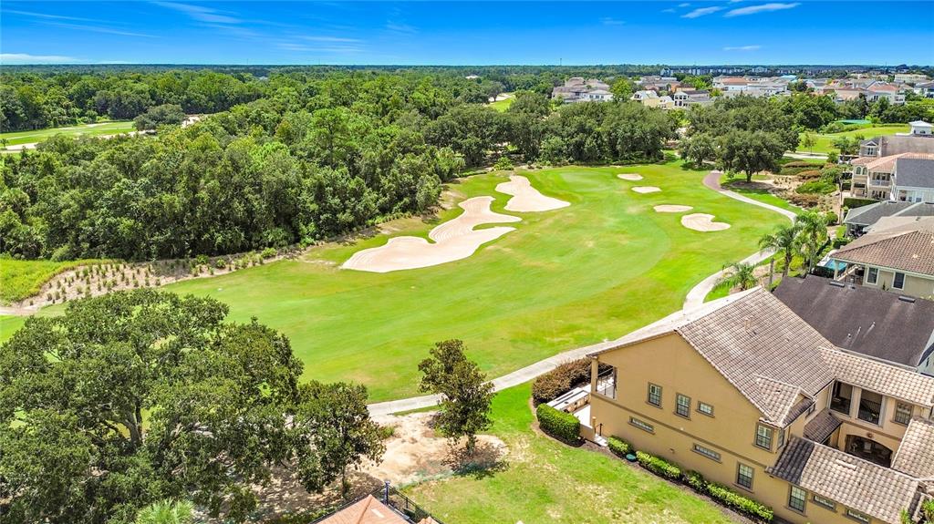 An aerial view shows a house overlooking a golf course with sand traps and trees — 1221 RADIANT STREET, KISSIMMEE, FL