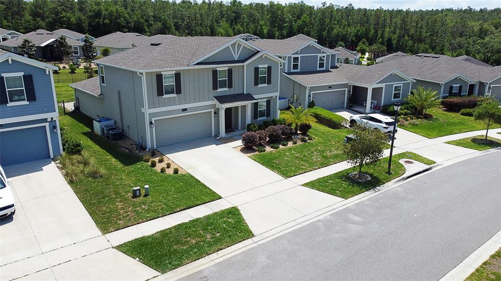 An aerial view shows a two-story gray house with a garage and a paved driveway — 5526 LIMESTONE STREET, MOUNT DORA, FL