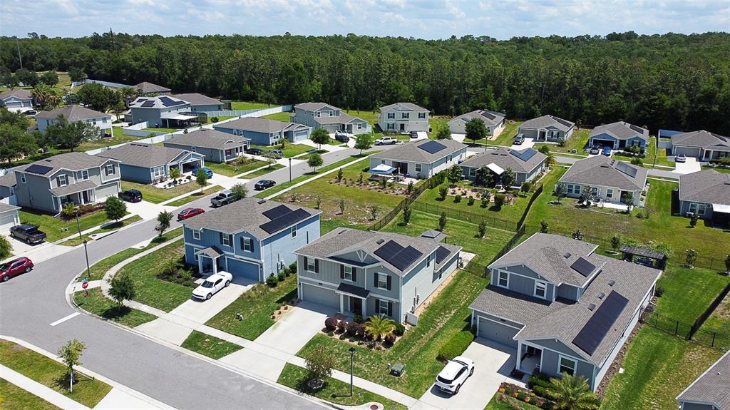 An aerial view of a suburban neighborhood featuring houses with solar panels and driveways — 5526 LIMESTONE STREET, MOUNT DORA, FL