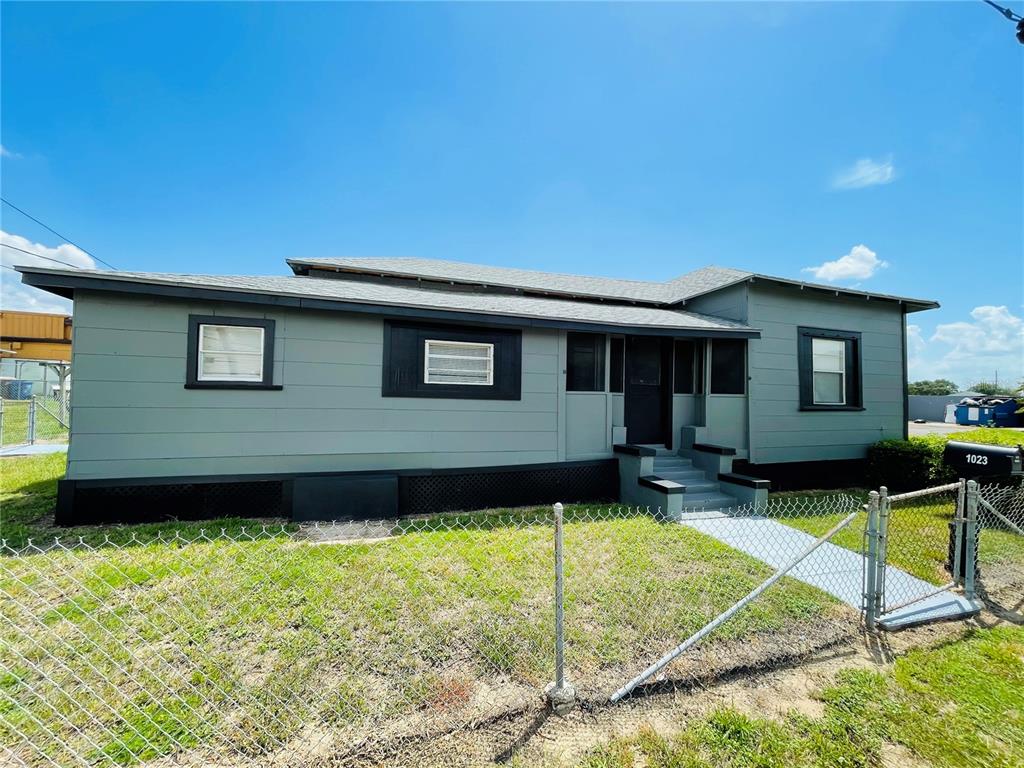 A single-story house with gray siding, black trim, and a chain-link fence in the yard — 1023 AVENUE D, HAINES CITY, FL