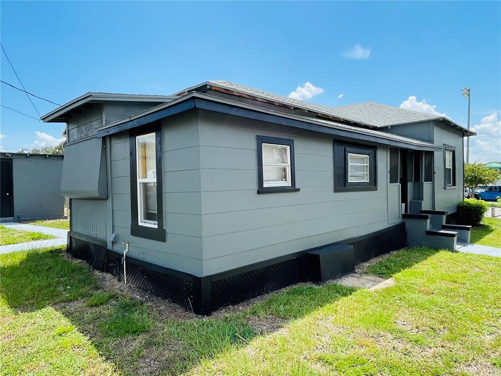 A gray, single-story house with black trim and a lattice-covered foundation under a blue sky — 1023 AVENUE D, HAINES CITY, FL