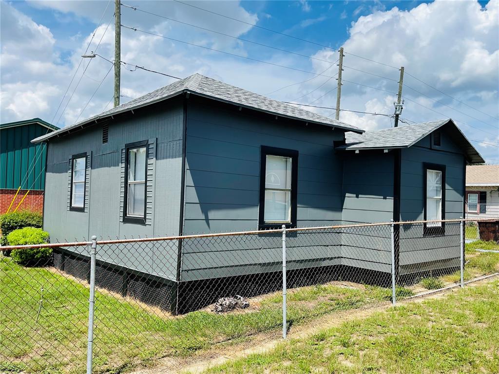 A gray, single-story house with black trim and a chain-link fence in the yard — 1023 AVENUE D, HAINES CITY, FL