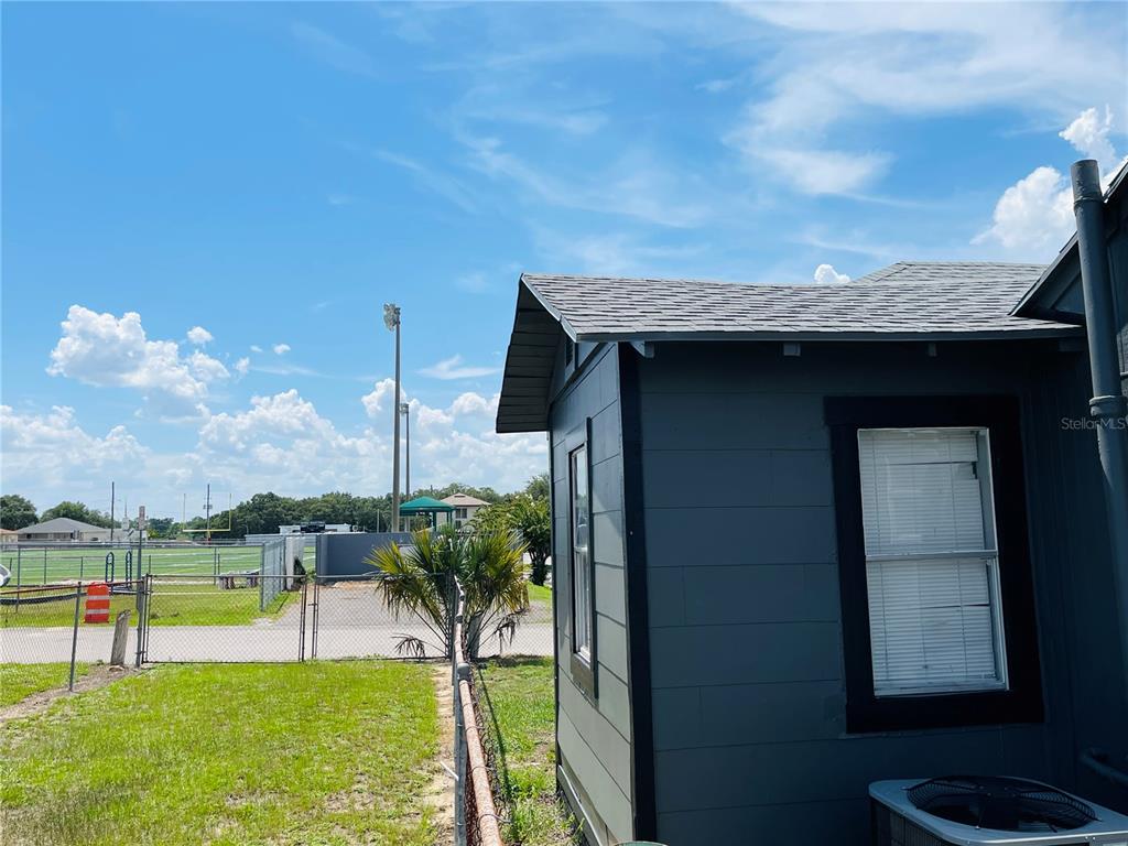 A view of a dark-sided house exterior with a window and an adjacent fenced yard — 1023 AVENUE D, HAINES CITY, FL