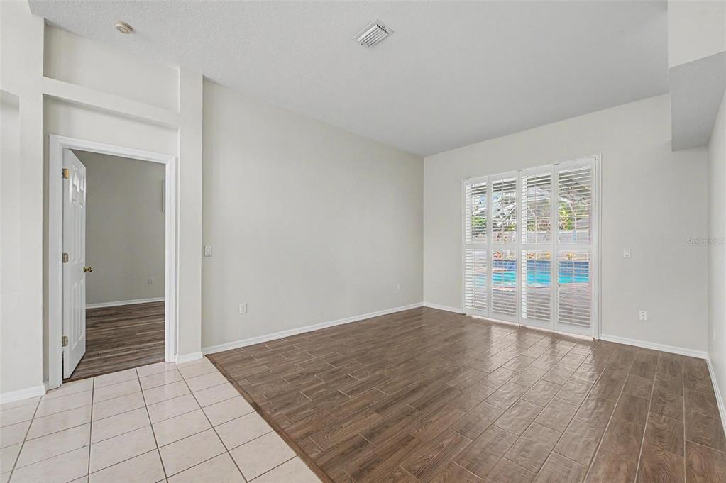 An empty room with wood-look tile flooring, white walls, and sliding glass doors to a pool — 4332 SWIFT CIRCLE, VALRICO, FL