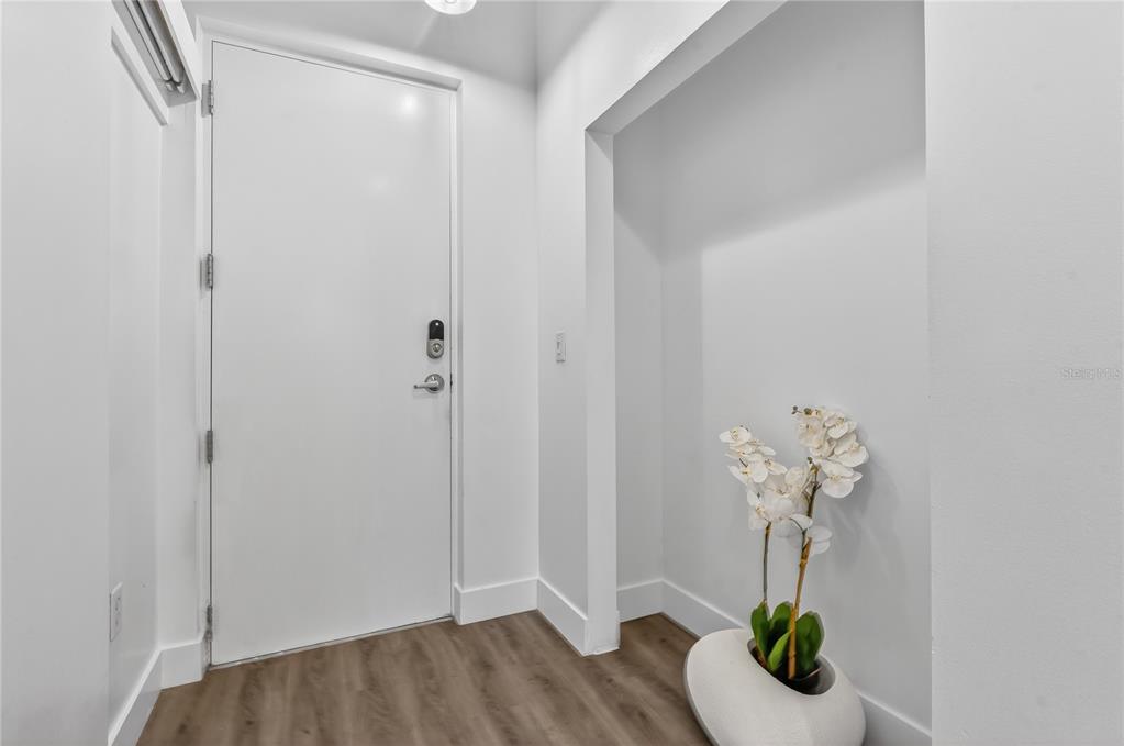 An entryway features a white door, light wood-look flooring, and a recessed alcove with flowers — 525 E JACKSON STREET UNIT 403, ORLANDO, FL