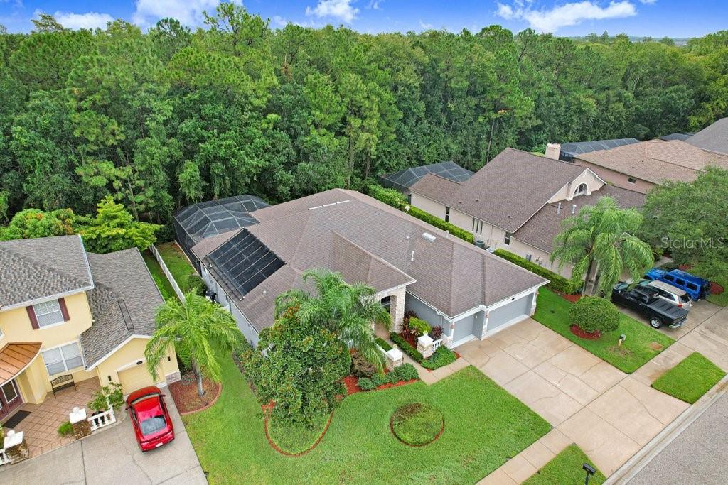 An aerial view shows a suburban house with a pool enclosure and solar roof panels — 16116 IVY LAKE DRIVE, ODESSA, FL