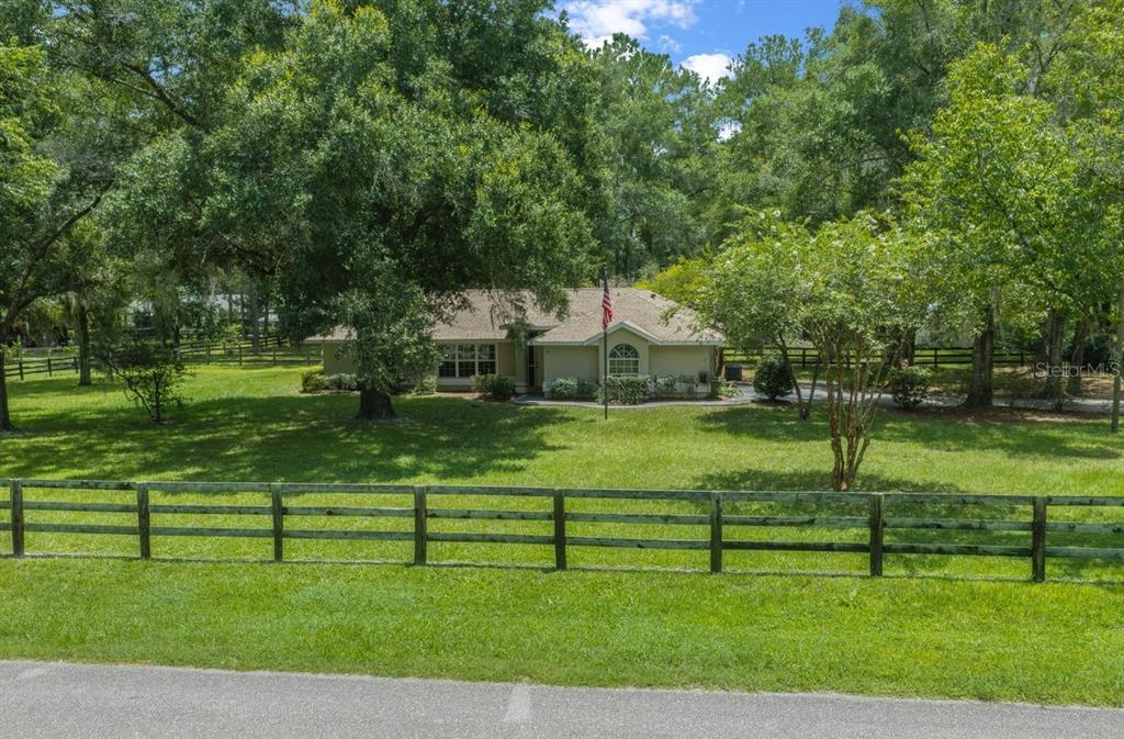 A single-story house with a tan exterior sits on a large, grassy, fenced-in lot — 4 HIALEAH DRIVE, OCALA, FL