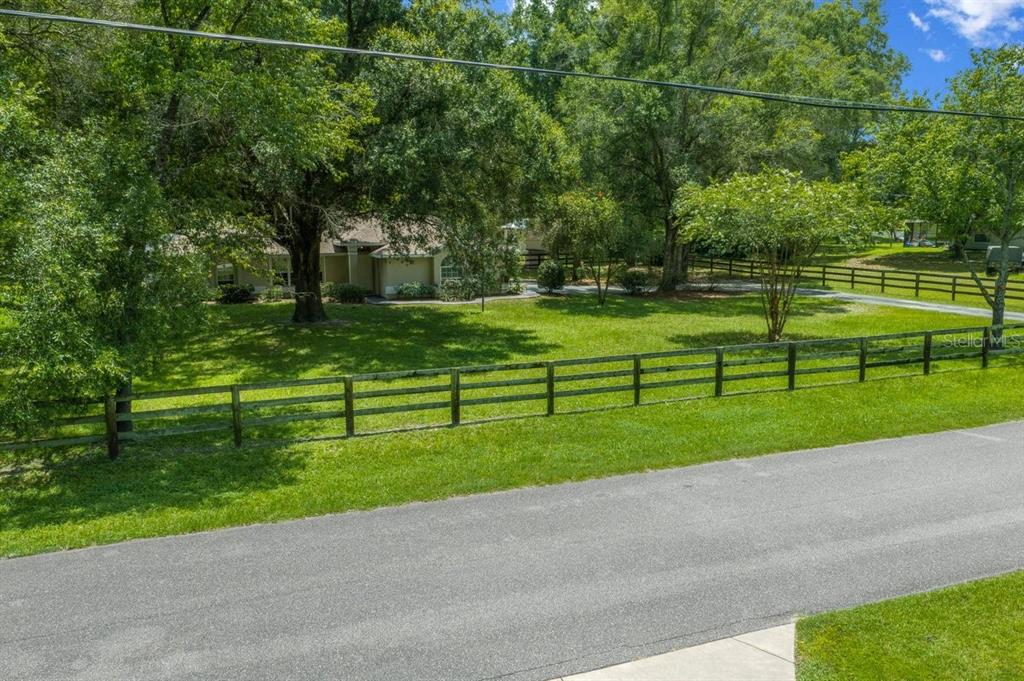 An exterior view of a house set back behind a wooden fence and grassy lawn — 4 HIALEAH DRIVE, OCALA, FL