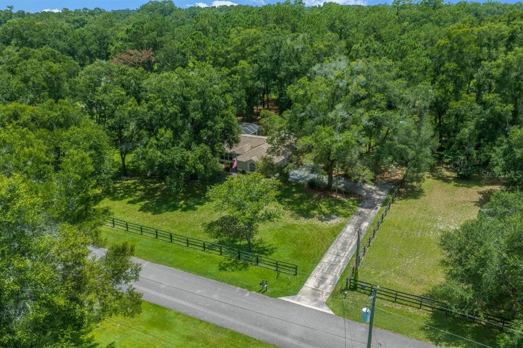 An aerial view shows a house with a pool enclosure surrounded by dense trees — 4 HIALEAH DRIVE, OCALA, FL
