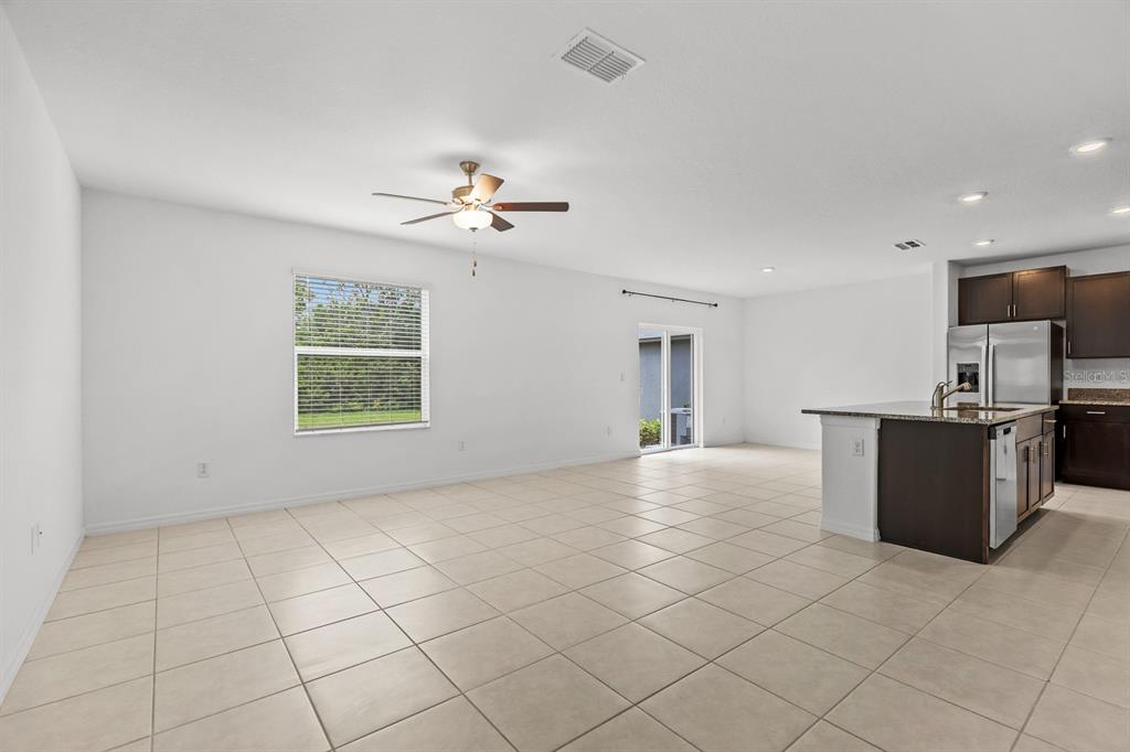 An open-concept living room features a beige sectional sofa, a coffee table, and a kitchen — 5552 BLUE AZURE DRIVE, WIMAUMA, FL