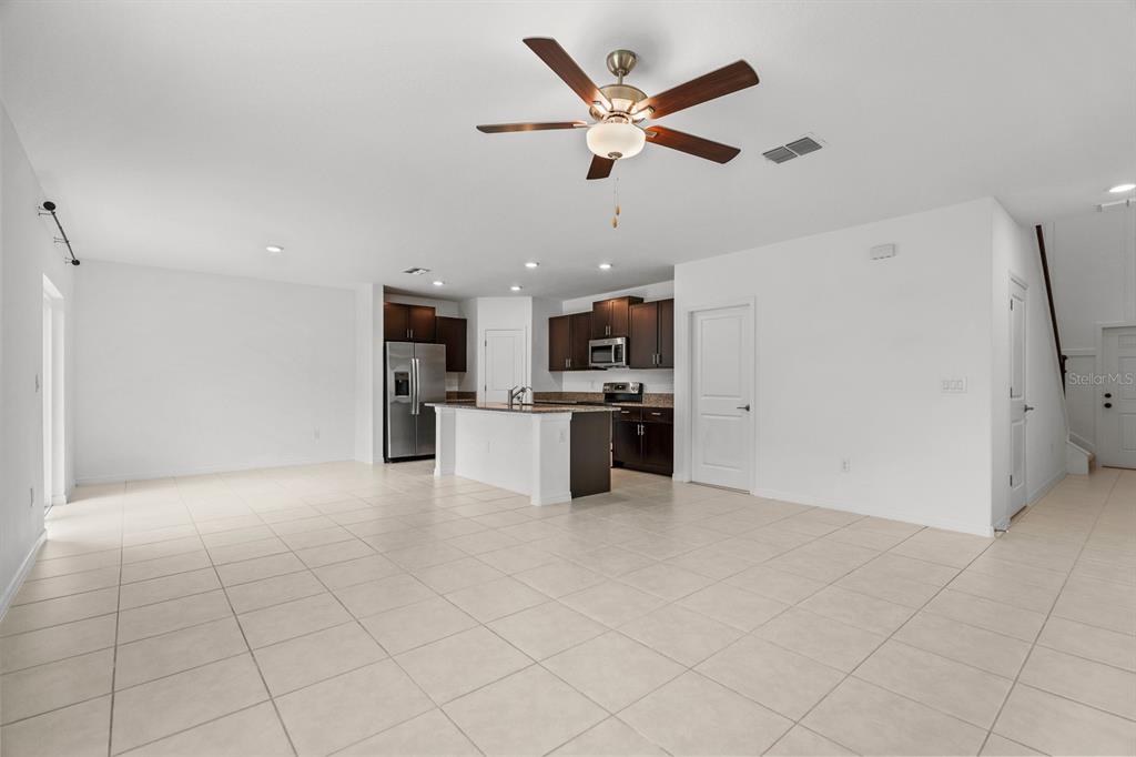 An open-concept living area features light tile flooring, a ceiling fan, and a kitchen island — 5552 BLUE AZURE DRIVE, WIMAUMA, FL