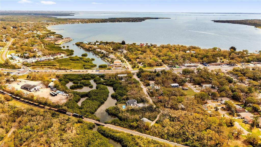 An aerial view shows a train traveling on tracks through a wooded area near water — PHOENIX AVENUE, OLDSMAR, FL