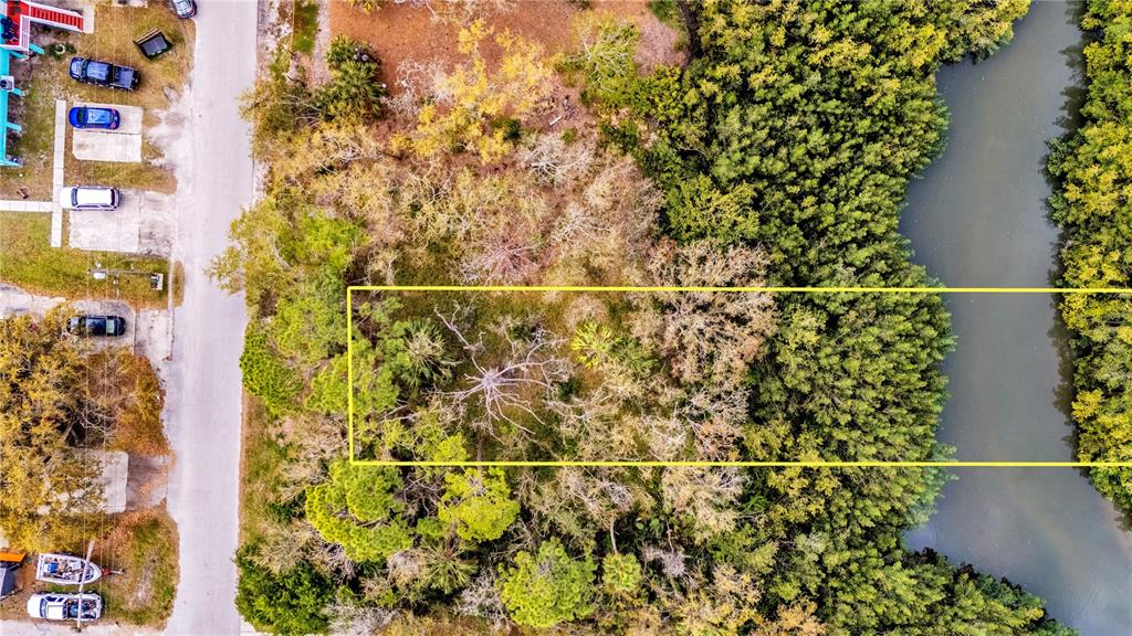 An aerial view shows a rectangular vacant lot outlined in yellow next to a waterway — PHOENIX AVENUE, OLDSMAR, FL