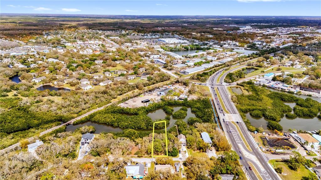 An aerial view shows a vacant rectangular lot outlined in yellow near a highway — PHOENIX AVENUE, OLDSMAR, FL