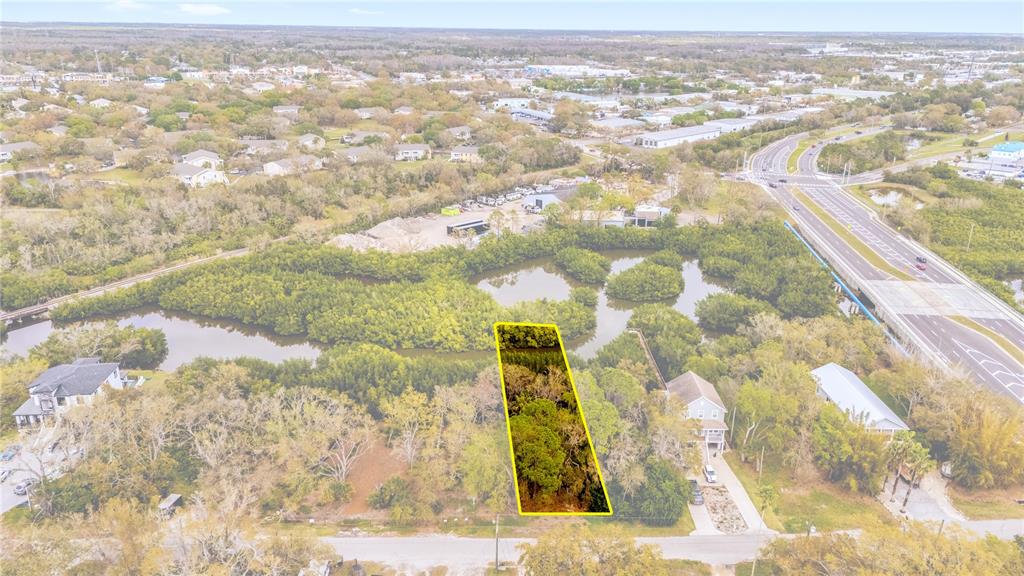 An aerial view shows a rectangular wooded lot highlighted in yellow near a waterway — PHOENIX AVENUE, OLDSMAR, FL