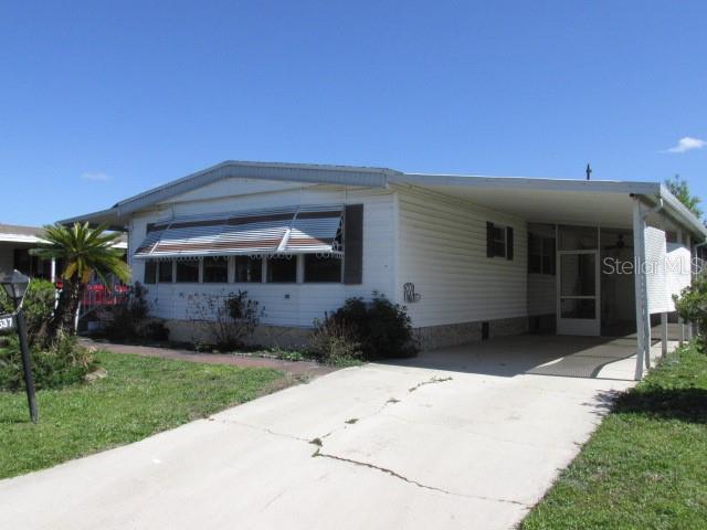 A single-story manufactured home with a carport, metal awnings, and a concrete driveway — 2537 LONGPINE LANE, ST CLOUD, FL