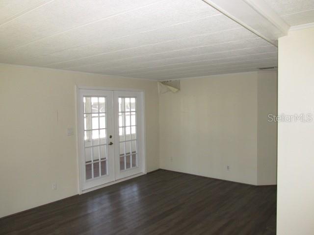 An empty room features white walls, a textured ceiling, and dark wood-look flooring — 2537 LONGPINE LANE, ST CLOUD, FL