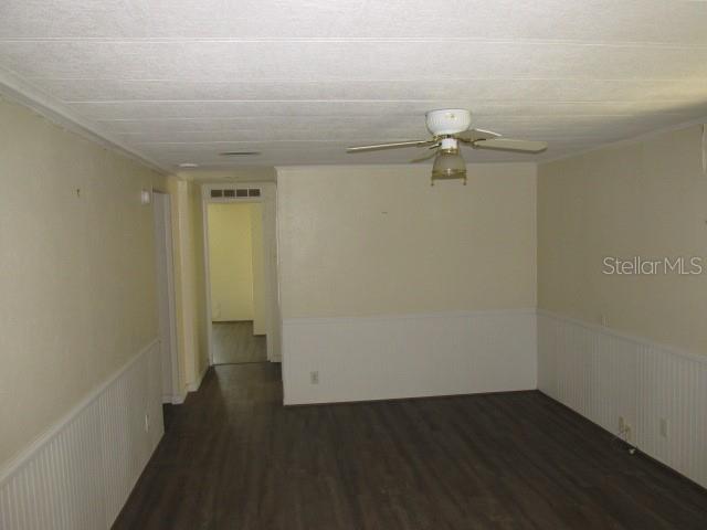 An interior room features dark wood-look flooring, white wainscoting, and a ceiling fan — 2537 LONGPINE LANE, ST CLOUD, FL