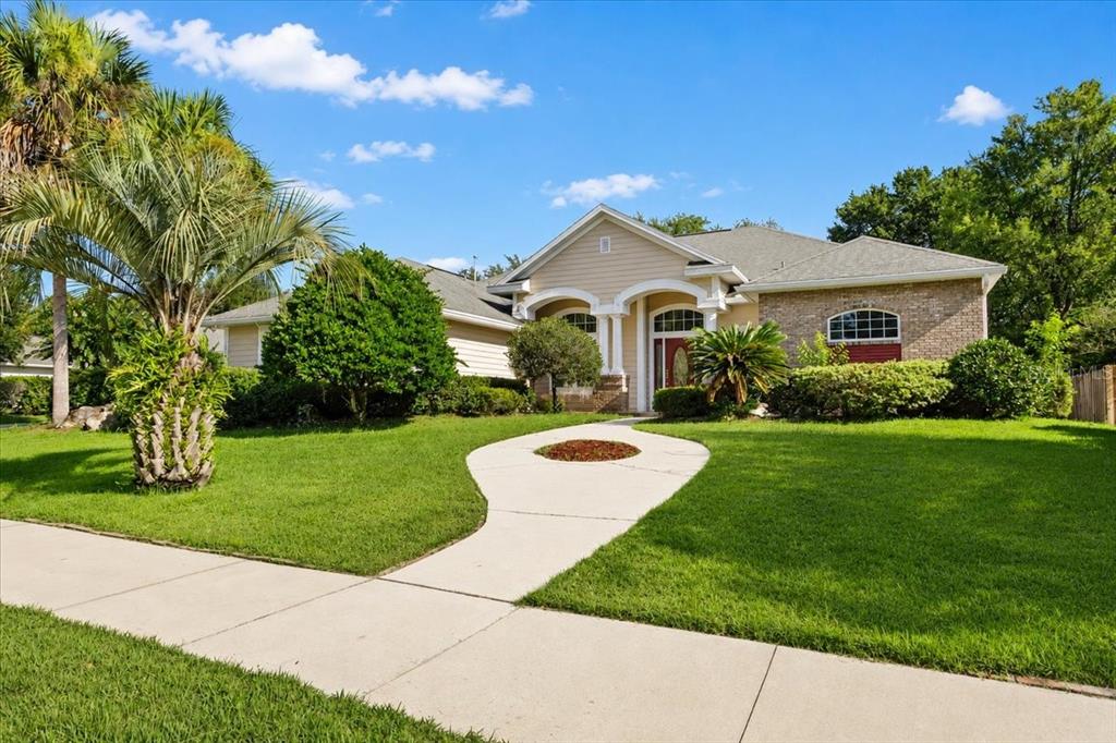A single-story house with a beige exterior, brick accents, and a curved concrete walkway — 14160 NW 29TH AVENUE, GAINESVILLE, FL