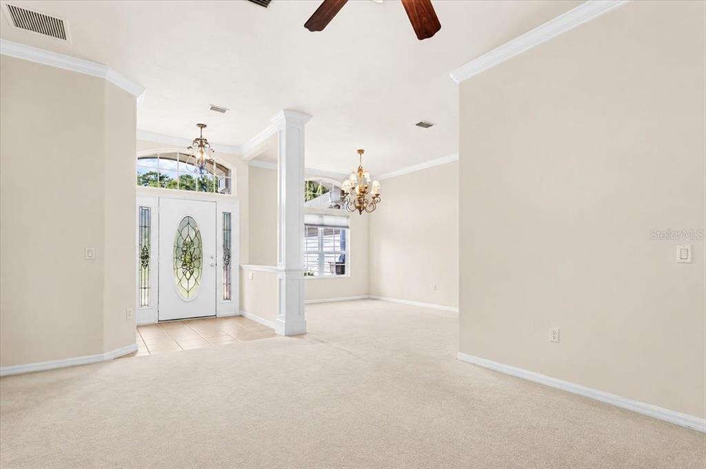A carpeted living area features a white front door, a column, and two hanging chandeliers — 14160 NW 29TH AVENUE, GAINESVILLE, FL