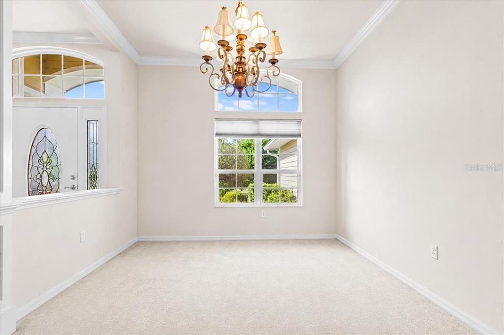 A dining room with beige carpet, a chandelier, and a large window with a transom — 14160 NW 29TH AVENUE, GAINESVILLE, FL