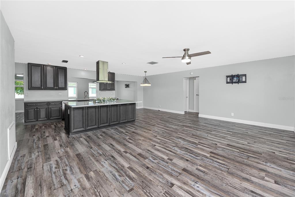 A spacious kitchen with dark cabinetry and a large island opens into a living area — 3455 100TH AVENUE N, PINELLAS PARK, FL