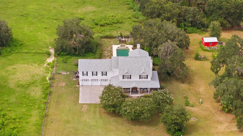 An aerial view shows a two-story house with a pool, garage, and surrounding grassy land — 13621 MCINTOSH ROAD, THONOTOSASSA, FL