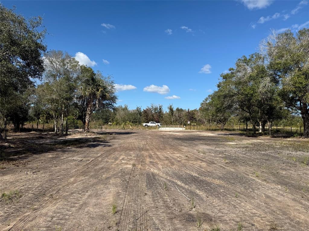 A wide, cleared dirt lot is surrounded by trees under a bright blue sky — 17618 NW 286TH STREET, OKEECHOBEE, FL