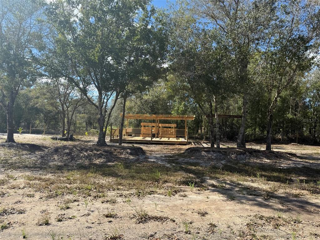 A wooden deck with a pergola and built-in seating sits in a wooded yard — 17618 NW 286TH STREET, OKEECHOBEE, FL