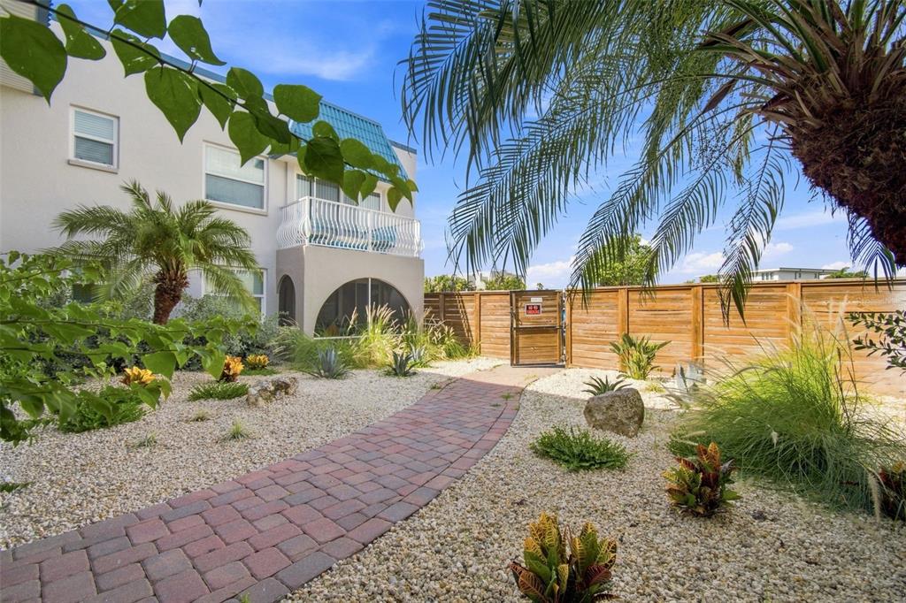 A swimming pool with blue lounge chairs sits on a brick patio beside a building — 17035 GULF BOULEVARD UNIT 216, NORTH REDINGTON BEACH, FL
