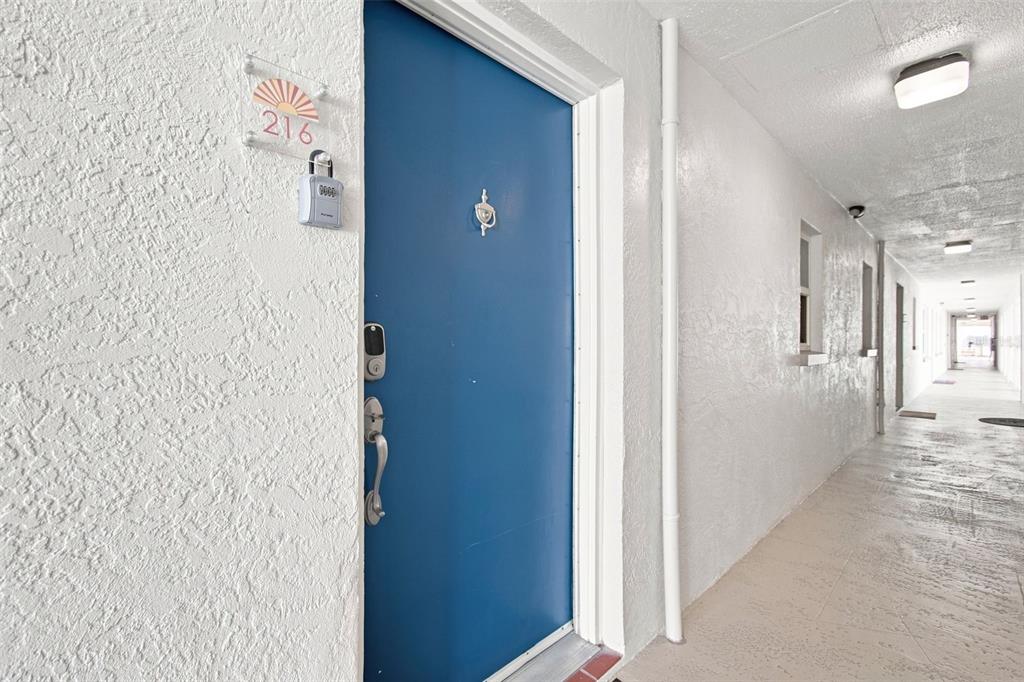 A kitchen with stainless steel appliances opens into a living room with wood-look flooring — 17035 GULF BOULEVARD UNIT 216, NORTH REDINGTON BEACH, FL