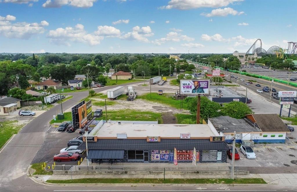 An aerial view shows a commercial building with a parking lot and nearby billboard signage — 9002 N 40TH ST, TAMPA, FL
